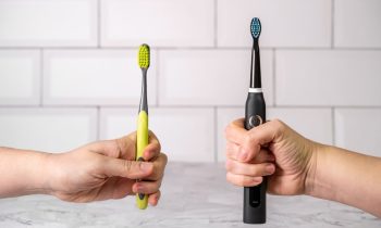 Deux mains tenant respectivement une brosse à dents manuelle et une brosse à dents électrique