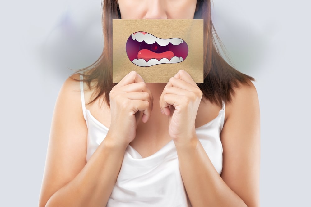 Femme cachant le bas de son visage avec une illustration de bouche avec une mauvaise haleine